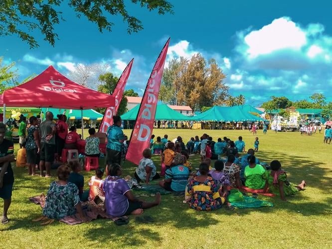 Things to do in Vanuatu: locals and visitors gather on a grassy field for a community festival with marquees and Digicel flags in the background